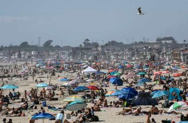 Galera lota as areias de Newport Beach em um sábado ensolarado.