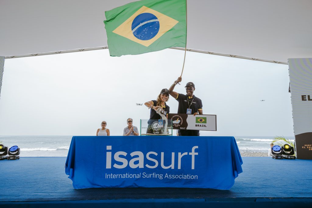 Chloé Calmon e Carlos Bahia carregam a bandeira brasileira na abertura do ISA World Longboard Championship 2023.