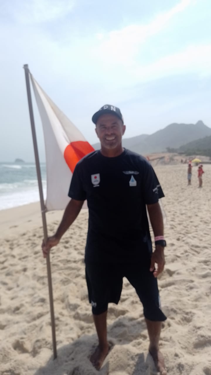 Vitinho na areia com a bandeira japonesa.